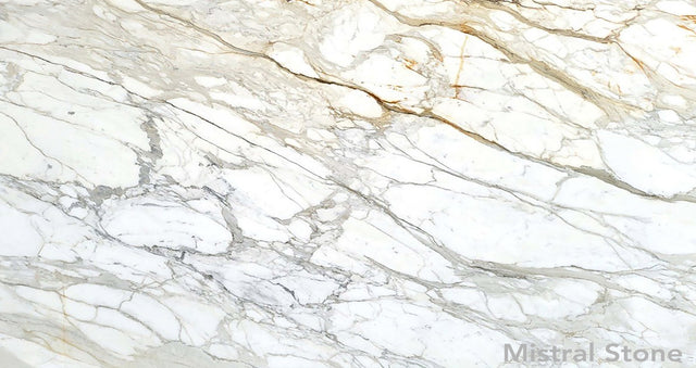 Premium Calacatta Gold marble slab featuring a luminous white background with dramatic grey and rich honey gold veining with customizable finishes by Mistral Stone