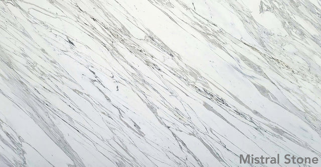 Calacatta premium Italian white marble slab featuring iconic bold diagonal grey veining on a luminous white background with customizable finishes by Mistral Stone