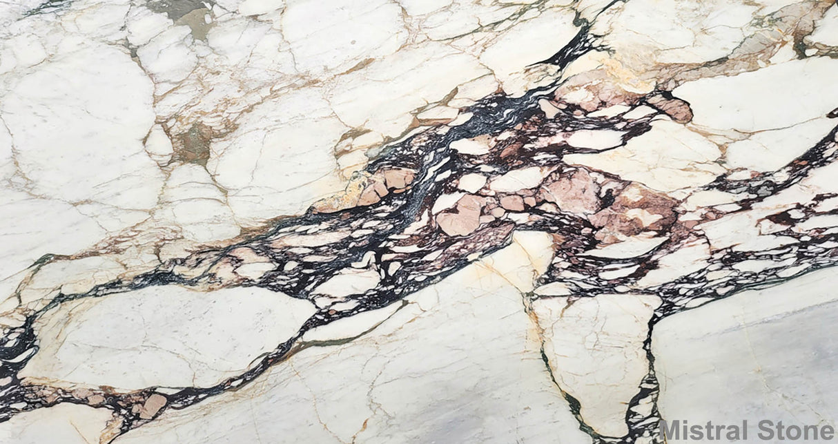 Premium Calacatta Viola Monet marble slab featuring a dramatic hybrid matrix of cabernet violet breccia, sage green, and ochre gold veins on a luminous white background with customizable finishes by Mistral Stone